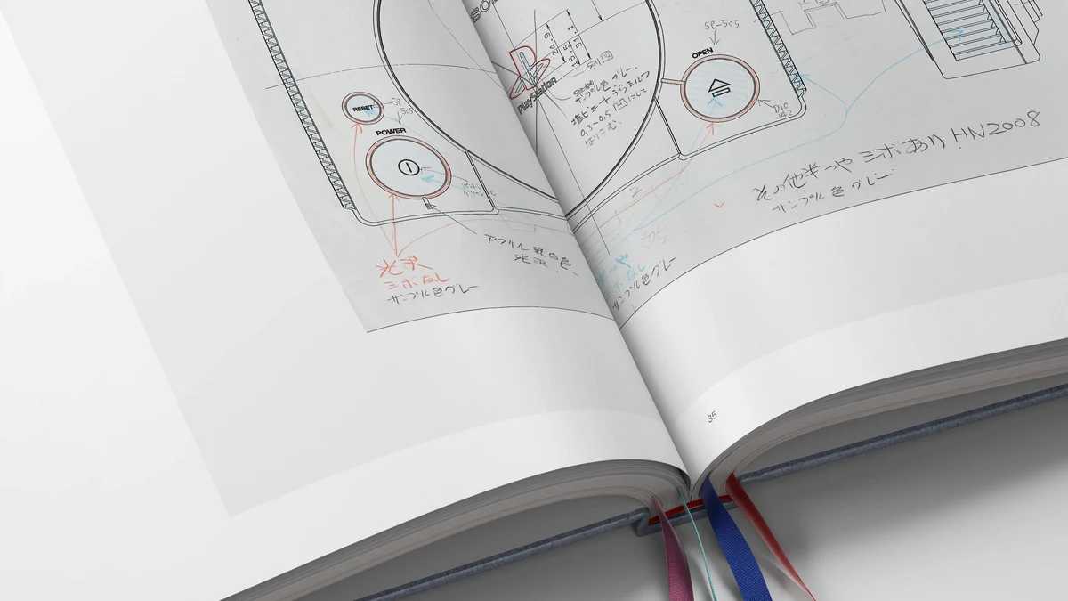 Plans techniques originaux annotés à la main par les ingénieurs de Sony et quadruple signet ruban aux couleurs des boutons PlayStation.